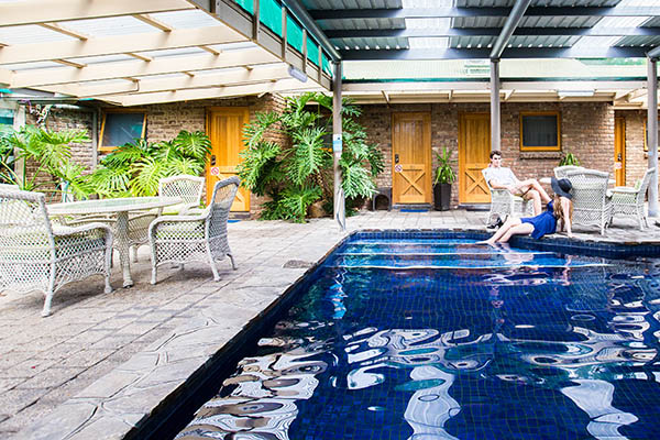 A couple sits by a pool, surrounding by rustic furniture