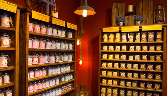 A dim-lit room, lined with large shelves stacked with colourful candles