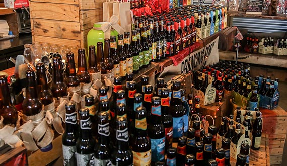 A variety of bottled beers with different coloured labels displayed upon wooden crates