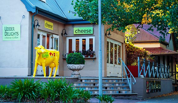 A building surrounded by green trees, with a bright yellow cow sculpture at the front